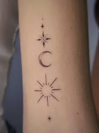 Pionowy ciąg drobnych gwiazd, cieniowanego półksiężyca i promienistego słońca wykonany cienką linią na ramieniu – tatuaż Oli, SHADY TATTOO Wieluń