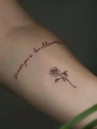 Odręczny napis „siempre brillarás” i mała róża na łodyżce wykonane cienką kreską na ręce – tatuaż Oli, SHADY TATTOO Wieluń