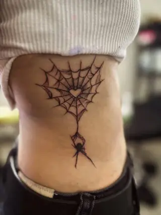 Tatuaż pajęczyny z serduszkiem i pająkiem na żebrach, czarny tusz – SHADY TATTOO Wieluń